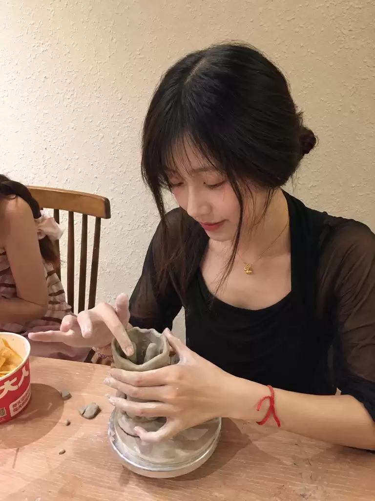 提示词：\n\n以上传人物照片作为唯一身份与面部参考 生成一组真实自然的陶艺体验生活照：成年女性 长黑发